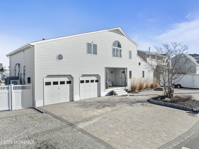 view of front of home featuring a garage, fence, and decorative driveway