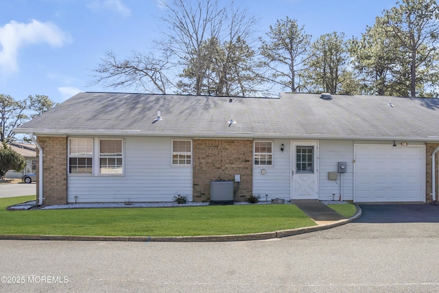 back of property featuring a garage, a shingled roof, aphalt driveway, and a lawn