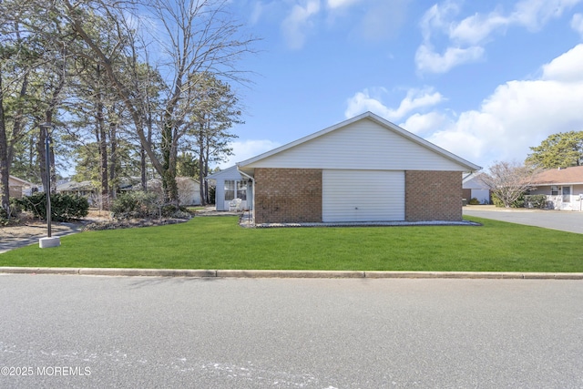 view of property exterior with a yard, brick siding, and driveway