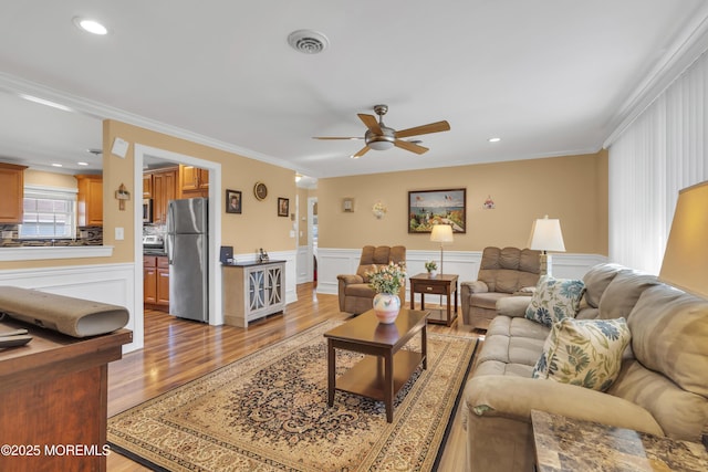 living room featuring recessed lighting, visible vents, ornamental molding, a ceiling fan, and wood finished floors