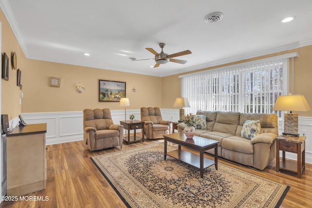 living room featuring light wood finished floors, ornamental molding, and a ceiling fan