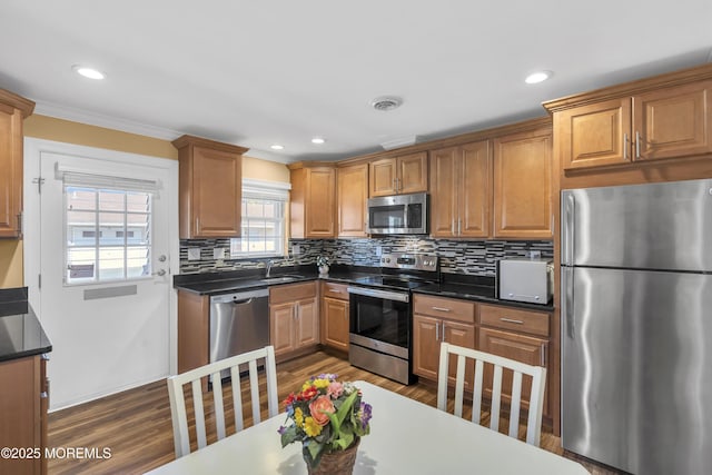 kitchen featuring stainless steel appliances, dark wood-style flooring, visible vents, tasteful backsplash, and dark countertops