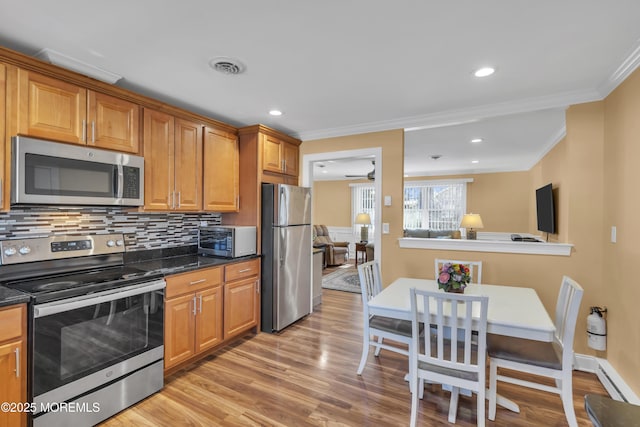 kitchen featuring visible vents, light wood-style floors, appliances with stainless steel finishes, backsplash, and crown molding