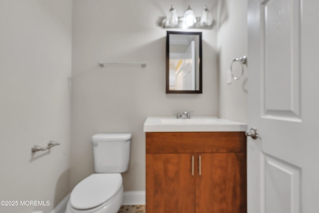 bathroom featuring toilet, baseboards, and vanity