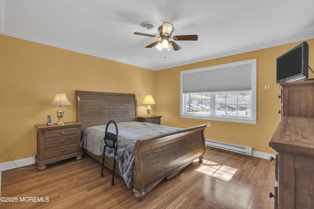 bedroom with wood finished floors, visible vents, baseboards, ornamental molding, and baseboard heating