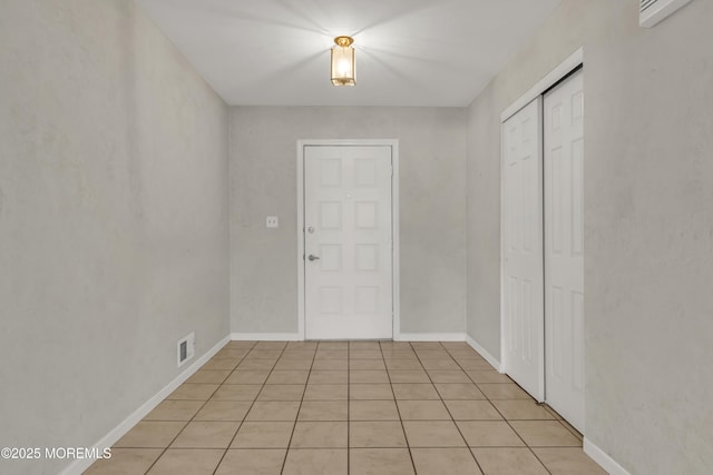 foyer entrance featuring light tile patterned floors, visible vents, and baseboards