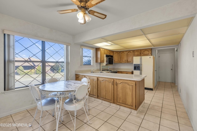 kitchen with a sink, stainless steel appliances, a peninsula, light countertops, and light tile patterned floors