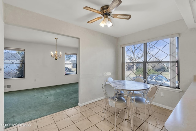 carpeted dining room with tile patterned flooring, ceiling fan with notable chandelier, visible vents, and baseboards