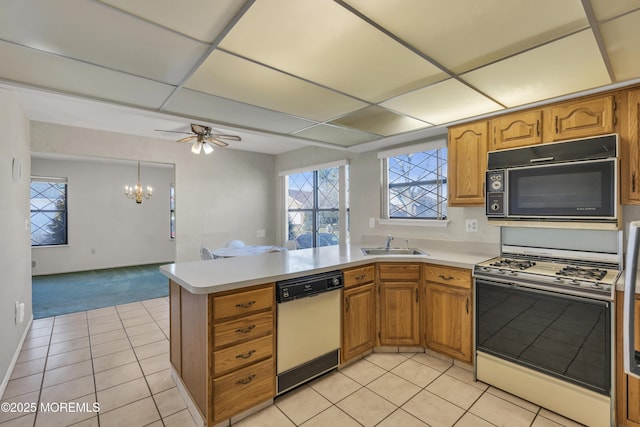 kitchen with black microwave, dishwasher, light countertops, white range with gas cooktop, and a sink