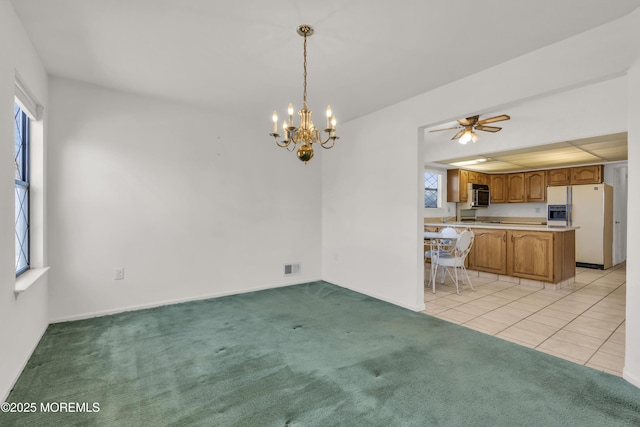 unfurnished dining area with light carpet, visible vents, ceiling fan with notable chandelier, and light tile patterned floors