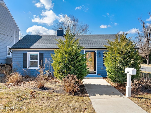 view of front of property featuring a shingled roof and a chimney