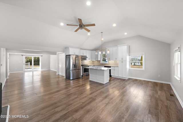 kitchen with stainless steel appliances, white cabinets, open floor plan, light countertops, and a center island