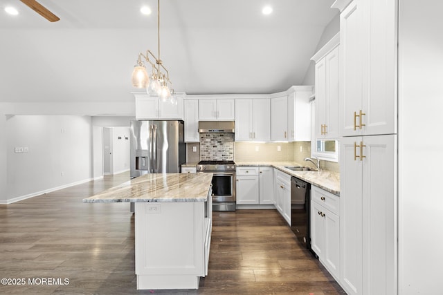 kitchen with under cabinet range hood, stainless steel appliances, vaulted ceiling, a center island, and tasteful backsplash