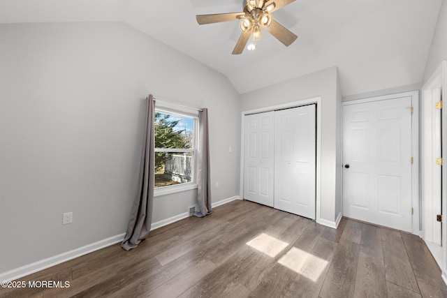 unfurnished bedroom with lofted ceiling, baseboards, and wood finished floors