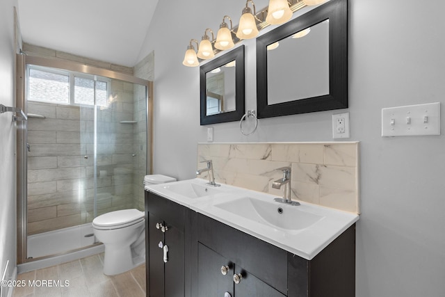 bathroom with a stall shower, a sink, toilet, and decorative backsplash