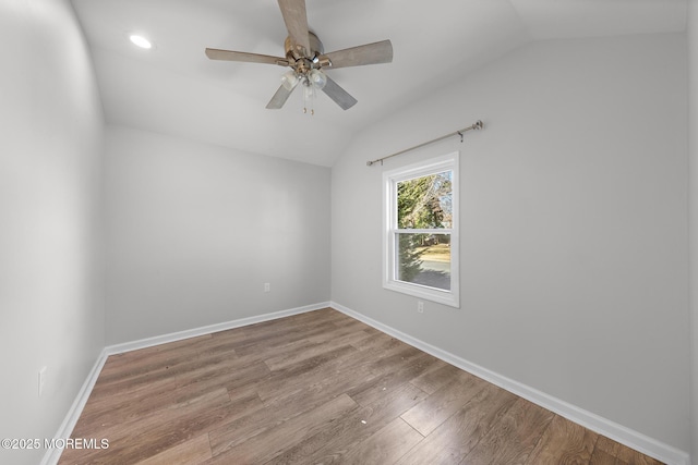 empty room featuring lofted ceiling, a ceiling fan, baseboards, and wood finished floors