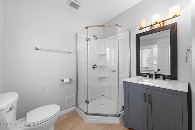 bathroom featuring a stall shower, visible vents, toilet, and wood finished floors