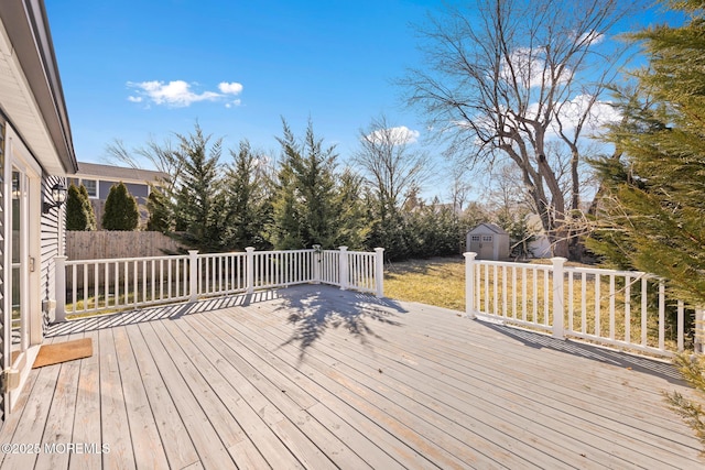 deck featuring a shed, fence, and an outbuilding