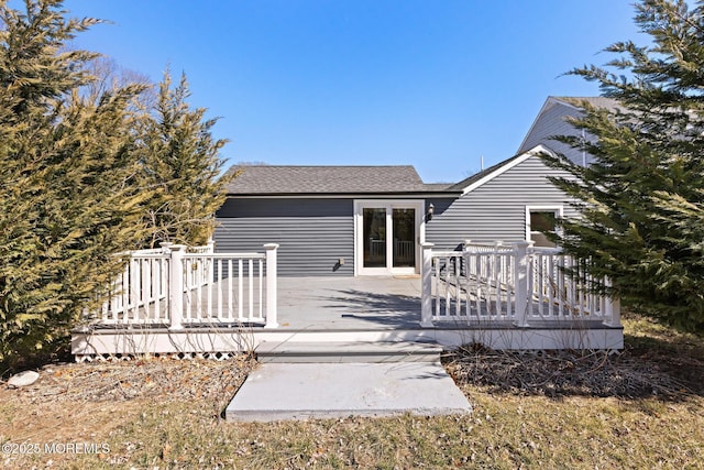 back of property with a shingled roof and a deck