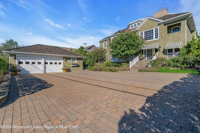 view of front of house with a chimney, decorative driveway, and an attached garage