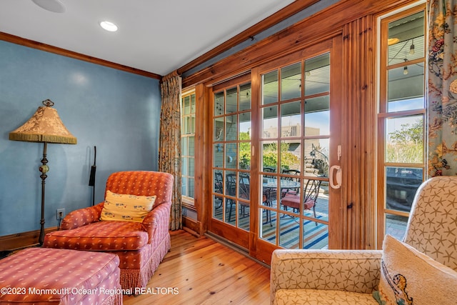 living area with hardwood / wood-style flooring and crown molding