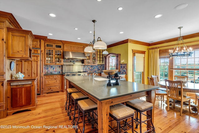 kitchen featuring light wood finished floors, ornamental molding, extractor fan, and brown cabinets