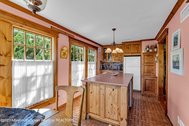 kitchen with ornamental molding, brick floor, a kitchen island, and freestanding refrigerator