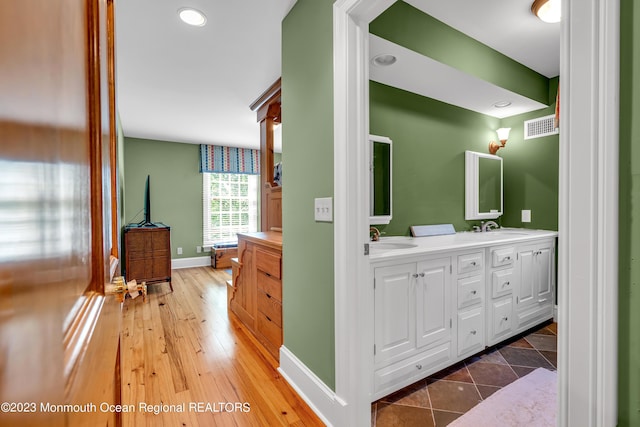 full bathroom with double vanity, a sink, visible vents, and baseboards