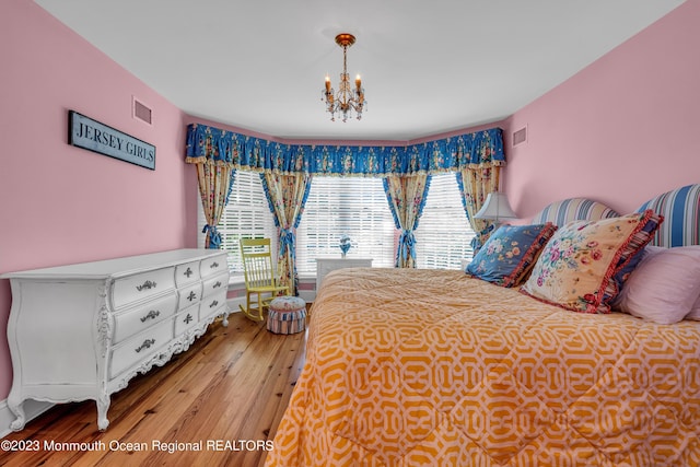 bedroom featuring a chandelier, wood finished floors, and visible vents