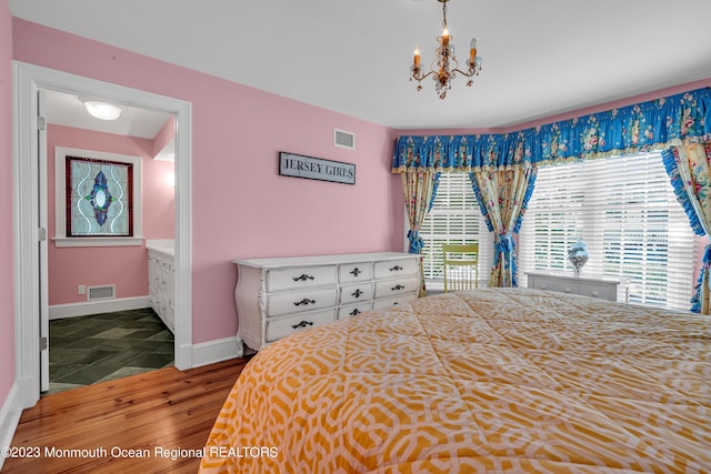 bedroom with a notable chandelier, baseboards, visible vents, and wood finished floors