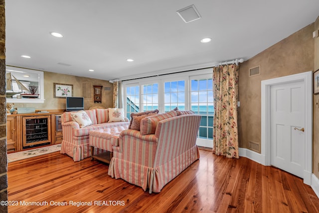 living room featuring wine cooler, visible vents, recessed lighting, and wood finished floors