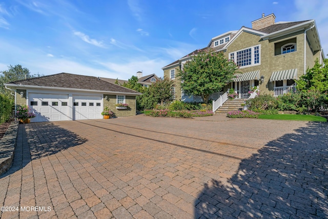 view of front of home with an attached garage, decorative driveway, and a chimney