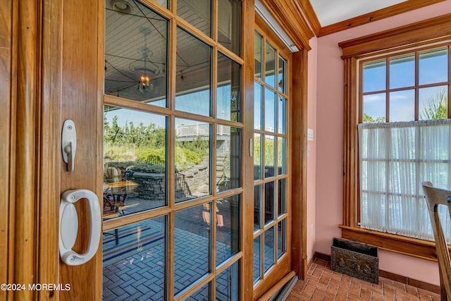 entryway featuring baseboards, brick floor, and crown molding