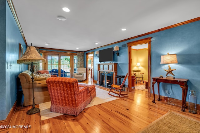 living area with recessed lighting, hardwood / wood-style floors, a fireplace with flush hearth, ornamental molding, and baseboards