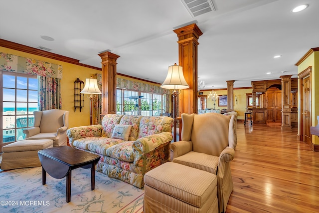 living area featuring decorative columns, recessed lighting, visible vents, ornamental molding, and light wood-type flooring