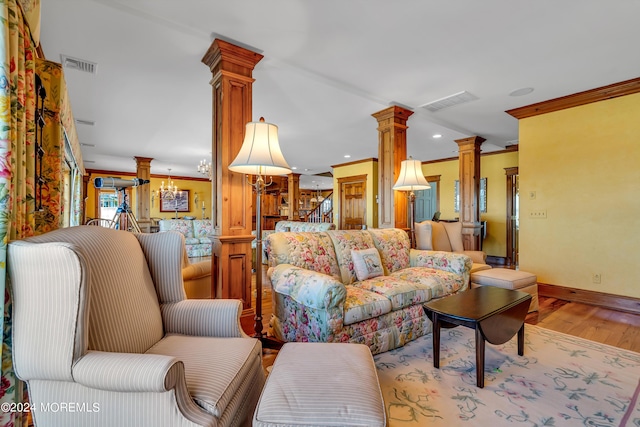 living room with decorative columns, visible vents, wood finished floors, and ornamental molding