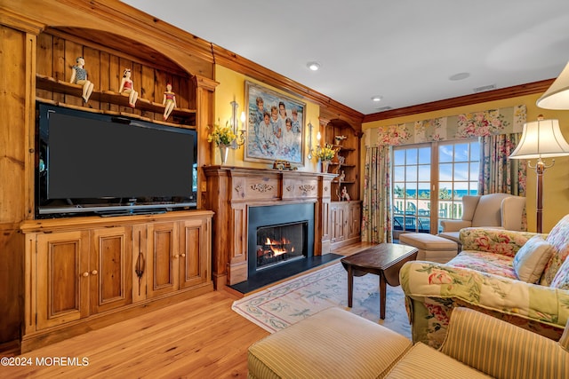 living area featuring light wood-style floors, a lit fireplace, visible vents, and crown molding