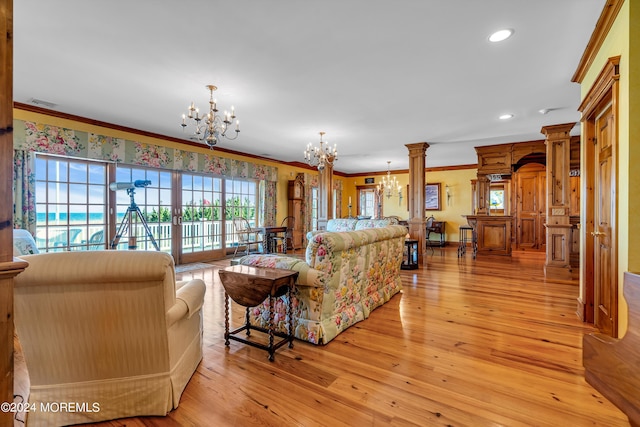 living area with decorative columns, visible vents, crown molding, light wood-type flooring, and a chandelier