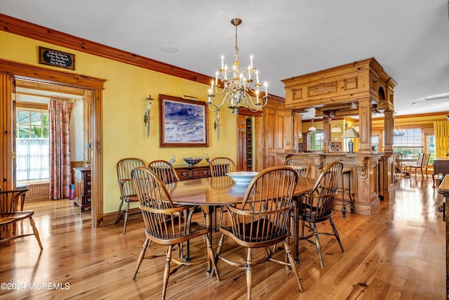 dining room featuring light wood finished floors, ornamental molding, baseboards, and ornate columns