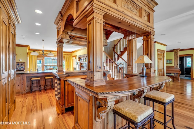 bar featuring ornamental molding, a wealth of natural light, and ornate columns