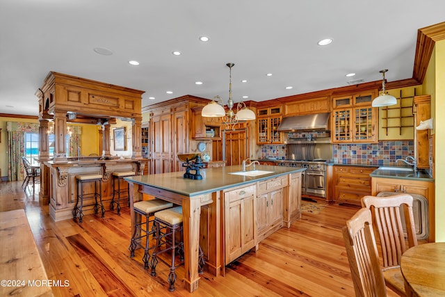 kitchen with a spacious island, ornamental molding, a sink, high end range, and exhaust hood