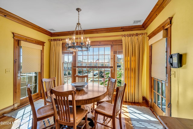 dining room with ornamental molding, a chandelier, visible vents, and wood finished floors