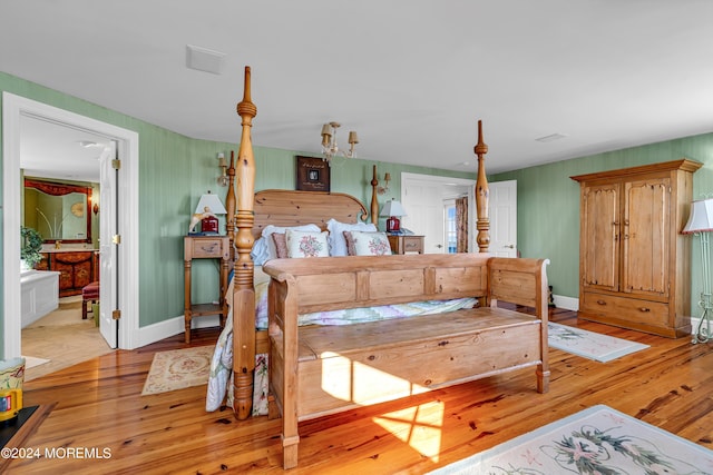 bedroom featuring baseboards, ensuite bathroom, and light wood-style floors