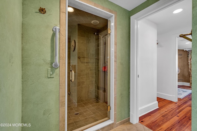 full bath featuring a shower stall, baseboards, and wood finished floors