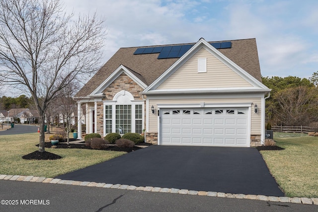 view of front facade with stone siding, driveway, a front lawn, and an attached garage