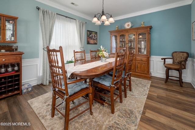 dining area with visible vents, a wainscoted wall, ornamental molding, wood finished floors, and a notable chandelier