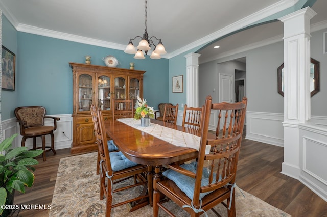 dining room featuring dark wood-style floors, a wainscoted wall, and ornate columns