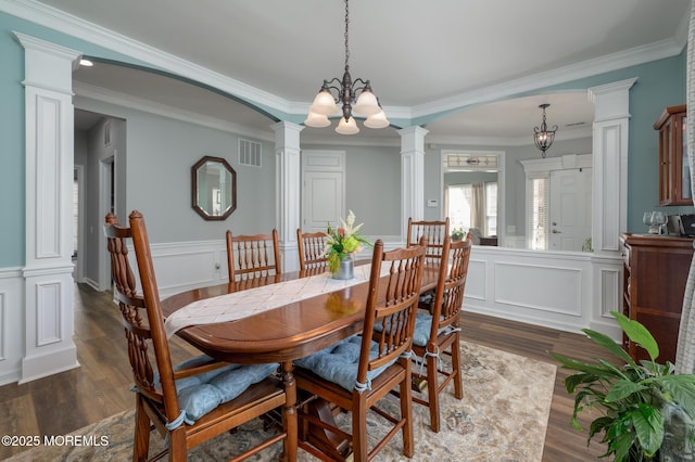 dining space with decorative columns, visible vents, dark wood finished floors, a wainscoted wall, and a chandelier