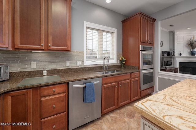 kitchen featuring stainless steel appliances, a fireplace, a sink, and tasteful backsplash