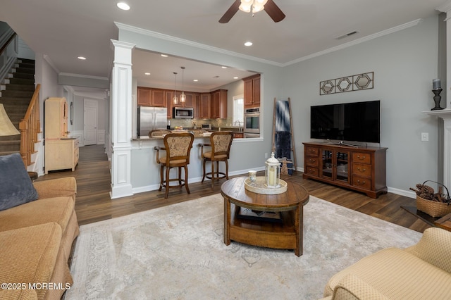 living room featuring stairway, wood finished floors, visible vents, and ornate columns